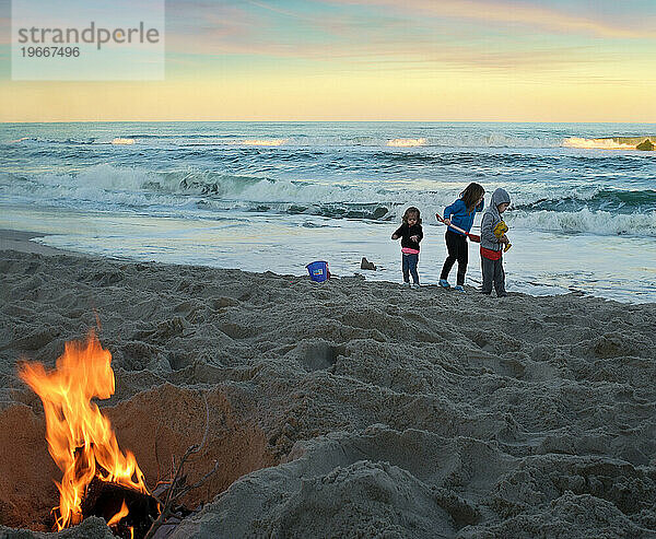 Drei kleine Kinder spielen im Sand mit Lagerfeuer