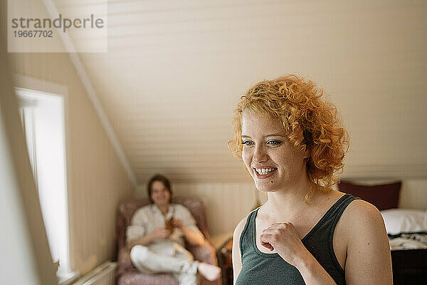 Fröhliche Frau mit lockigem Haar im Schlafzimmer neben ihrem Freund