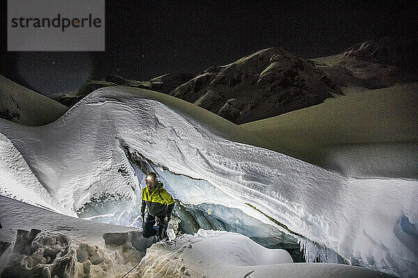 Bergsteiger geht am Rand einer Gletscherhöhle spazieren