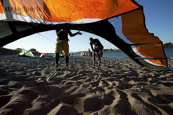 Menschen (Kiteboarder)  Drachen und Strand  umrahmt von einem Drachen in schönem Licht.