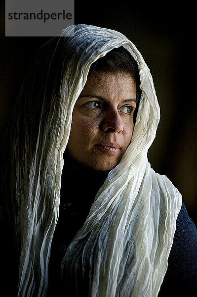 Eine mit einem Schal bedeckte Frau starrt aus dem Fenster einer großen Moschee.