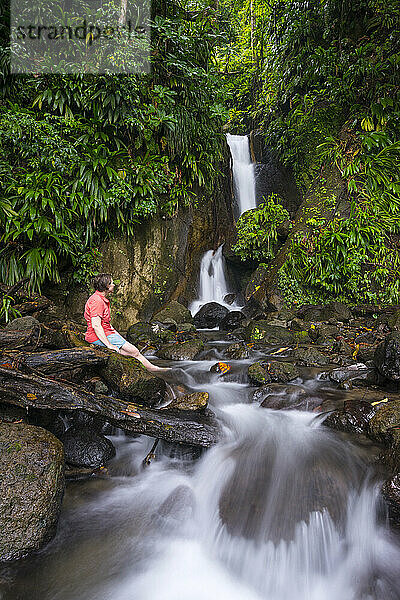 Eine Frau entspannt sich an einem wunderschönen Wasserfall in Trafalgar im Papillote Wilderness Retreat am Endpunkt von Abschnitt 3 des Waitukubuli National Trail auf der Karibikinsel