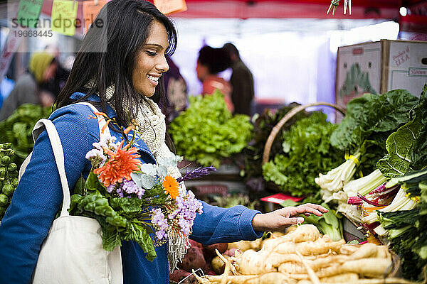 Eine junge Frau kauft an einem kühlen Herbsttag auf dem Ballard Farmer's Market frische Produkte ein.