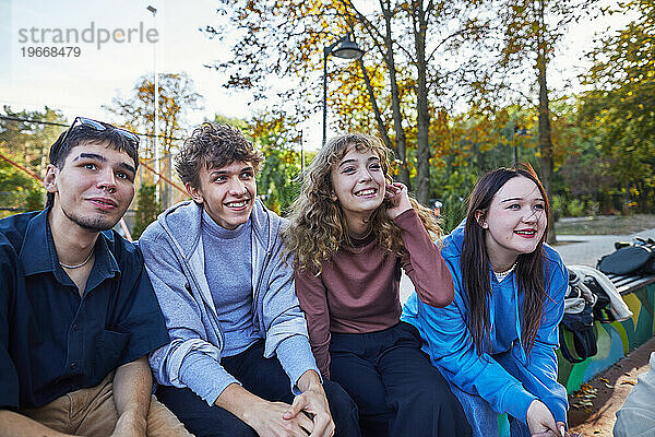 Gruppe fröhlicher Teenager  die im Park sitzen