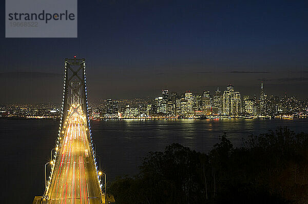 Nachts fahren Autos über die Bay Bridge in Richtung der Skyline von San Francisco  Kalifornien.