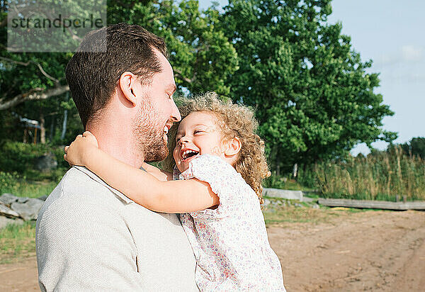 Vater und Tochter lachen gemeinsam am Strand