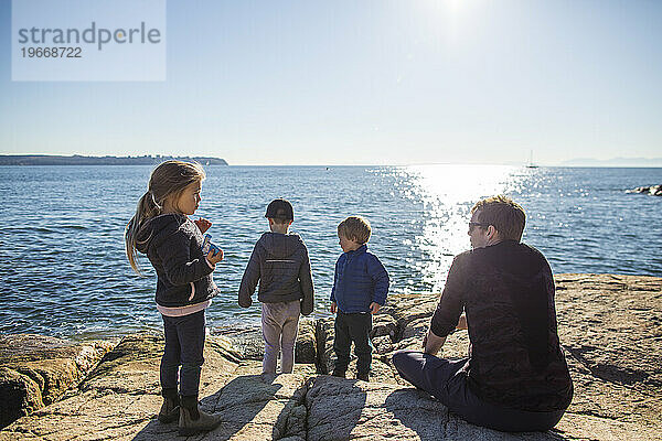 Vater genießt mit seinen drei Kindern einen Tag am Meer.