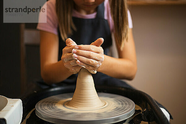 Ein Mädchen  das mit Ton auf einer Töpferscheibe arbeitet  aus nächster Nähe. Tradition