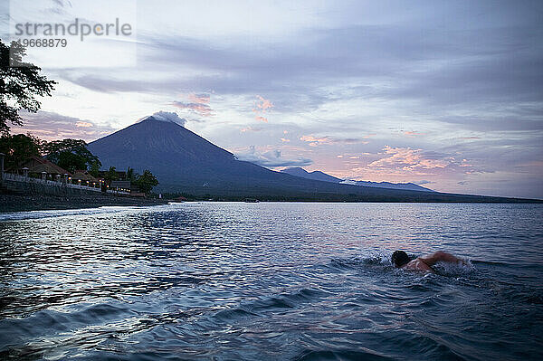 Ein Schwimmer schwimmt in Richtung Gunung Agung im westlichen Teil von Bali  Indonesien