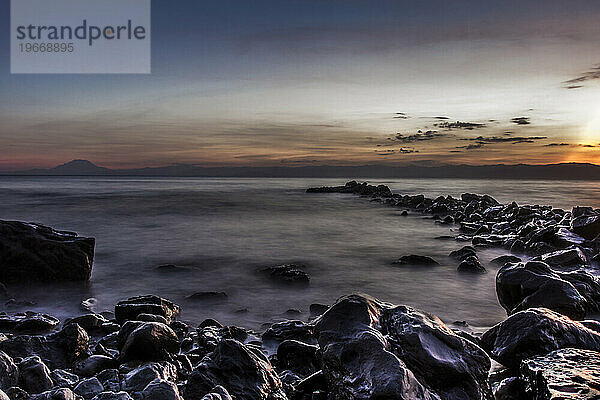 Steinsteg  der vor Sonnenaufgang ins Meer führt.