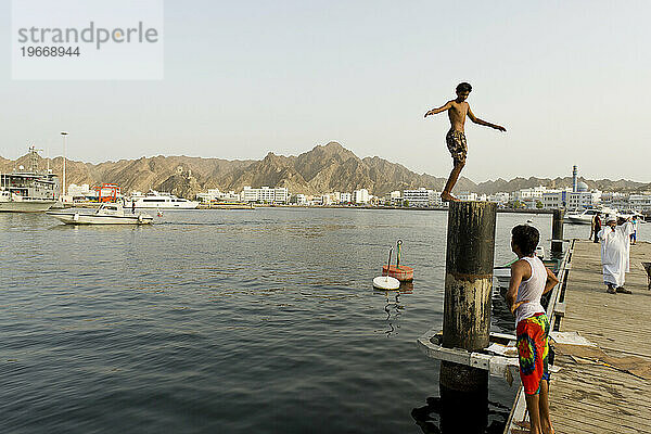 Ein Junge taucht ins Wasser des Hafens Sultan Qaboos in Maskat  Oman.