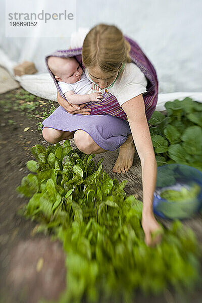 Frau und ihr Baby machen Gartenarbeit.