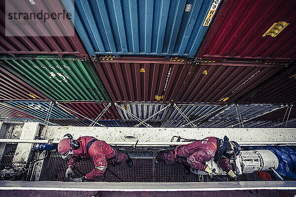 Arbeiter warten auf See ein Containerschiff