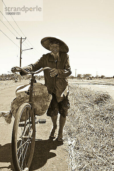 Farmer pushing bike in Indonesia.
