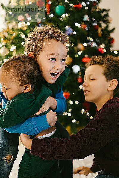 Brüder zusammen glücklich mit Weihnachtsbaum und Geschwisterliebe