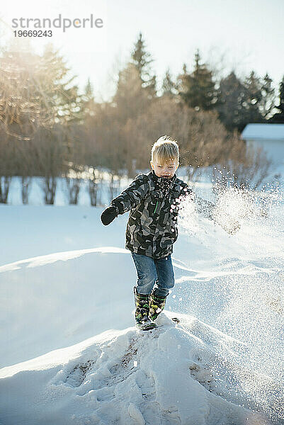 Vorderansicht eines kleinen Jungen in Schneeausrüstung  der auf dem Schnee steht