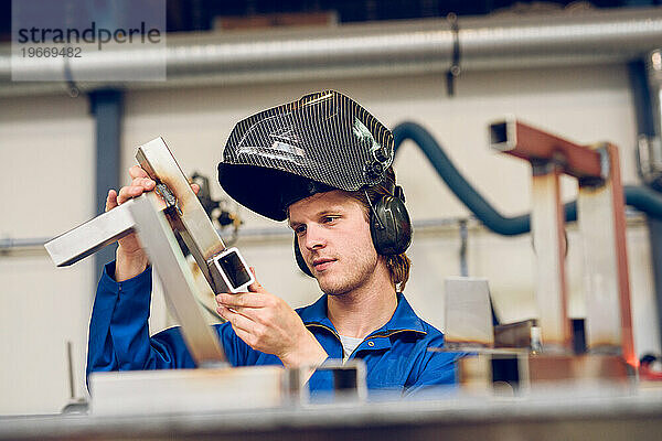 Konzentrierter Mann mit Helm  der in der Fabrik arbeitet