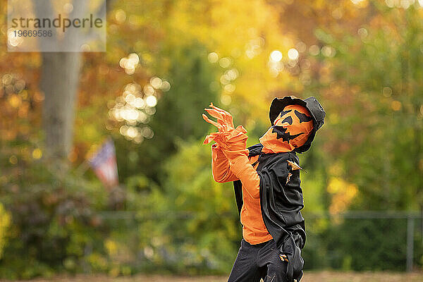 Kleines Kind posiert in einem gruseligen Kürbis-Halloween-Kostüm.