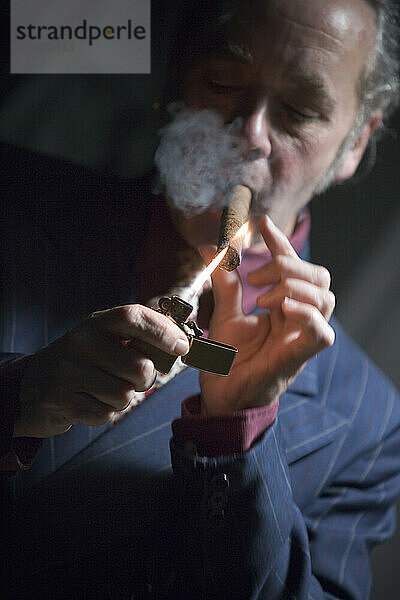 Vorderansicht eines Mannes  der sich eine Zigarre anzündet.