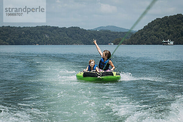 Kinder haben Spaß beim Tubing hinter einem Skiboot auf einem See