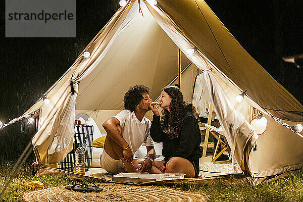 Verliebtes Paar isst Pizza in einem Campingzelt