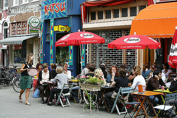 Menschen sitzen in einem Café im Freien in der Helstraat  einer trendigen Straße in der Nähe der Albert Cuypstraat  Amsterdam  Holland.