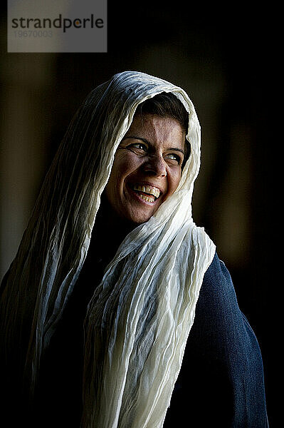 Eine mit einem Schal bedeckte Frau starrt aus dem Fenster einer großen Moschee.