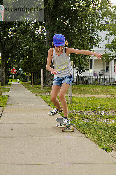 Skater-Mädchen macht Tricks auf dem Bürgersteig