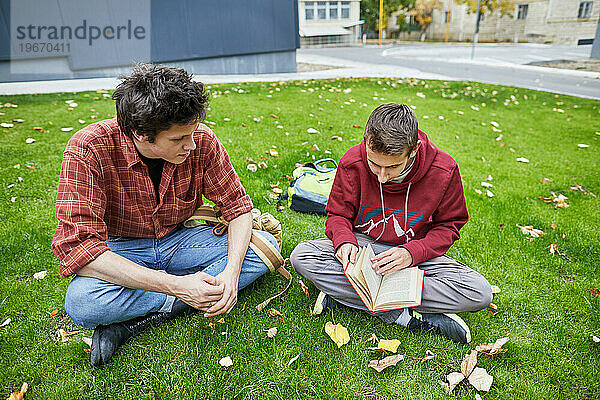 Jungs schauen sich ein Buch auf dem Schulhof an