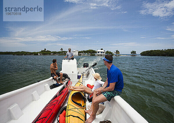 Kajakfahrer fahren in einem Motorboot in Ambergris Cay  Belize  aufs Meer hinaus.