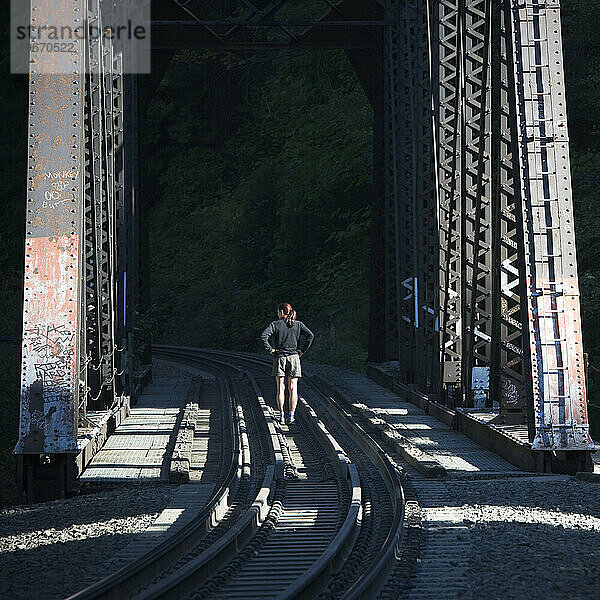 Eine Frau steht auf einer Eisenbahnbrücke.