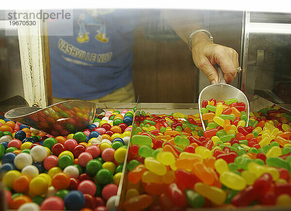 Eine Arbeiterin in einem Süßwarenladen schaufelt für einen Kunden Gummibärchen.