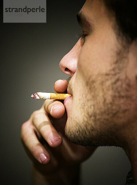 Ein junger Mann inhaliert eine Zigarette.