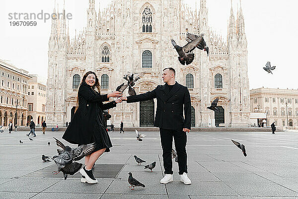 Ein Mädchen und ein Mann vor dem Mailänder Dom mit fliegenden Tauben