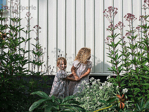 Ältere Schwester hält die Hand ihrer jüngeren Schwester durch die Blumen