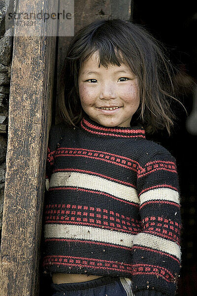 Junges Mädchen lehnt in Bhutan an der Tür.