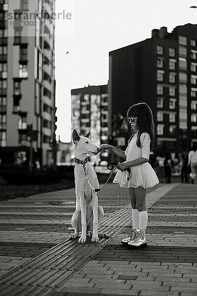 Mädchen mit weißem Hund auf einem Spaziergang in der Stadt.