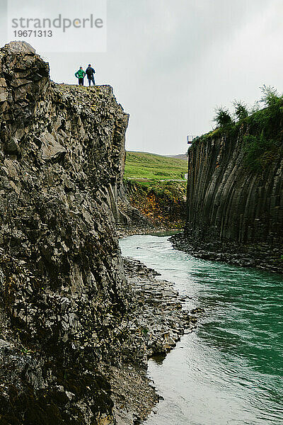 Zwei Personen auf einer Klippe bei einer Wanderung über dem Flusstal im Abenteuer