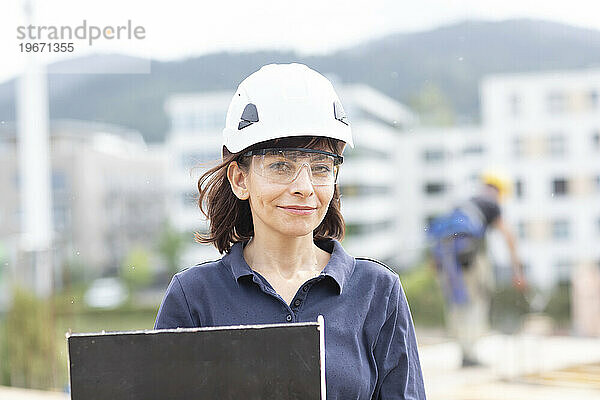 Ingenieurfrau  die draußen mit Helm arbeitet