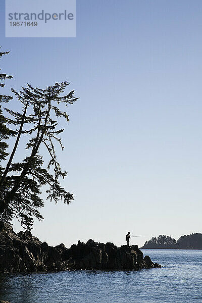 Die Silhouette eines Mannes vor blauem Himmel fischt vor der Küste von Vancouver Island.