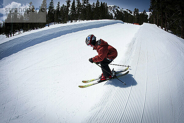 Junger Skifahrer fällt in eine Halfpipe.