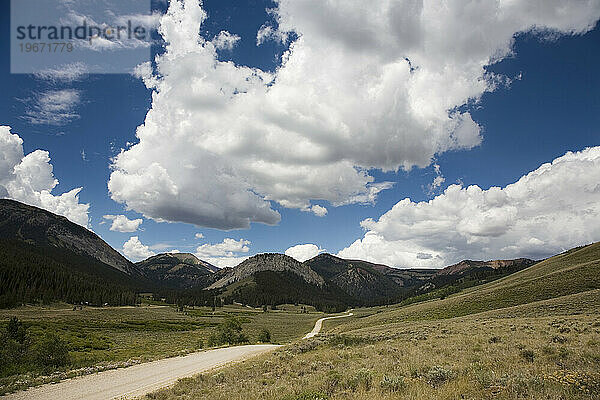 A long dirt road winds near the the foothills of the Rockies in Montana.