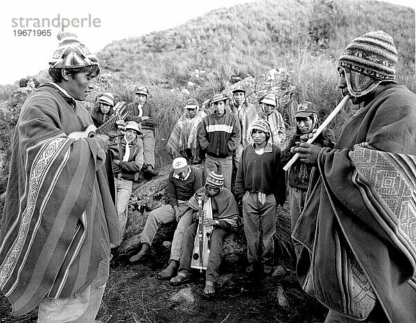 ANDEN  PERU – Quechuan-Indianer arbeiten als Träger entlang des Inka-Pfades nach Machu Picchu und entspannen sich am Ende eines Tages auf einem Gipfel  indem sie ihre traditionellen Instrumente spielen.Quelle: Susana Ra