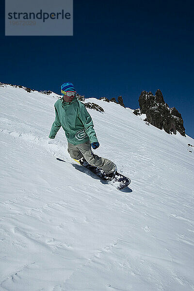 Snowboarder fahren bei frühlingshaftem Wetter mit schöner Aussicht.