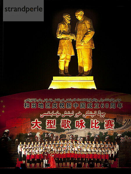 Kulturaufführung unter einer Statue von Mao und einem älteren Uiguren in Hotan  Xinjiang  China.