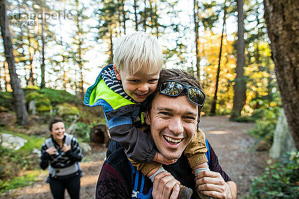 Vater und Sohn lachen gemeinsam beim Wandern im Park.
