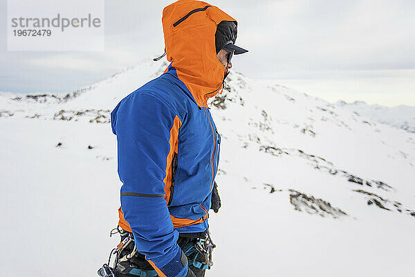 Seitenansicht eines Mannes auf windigem Berggipfel  warme Kleidung