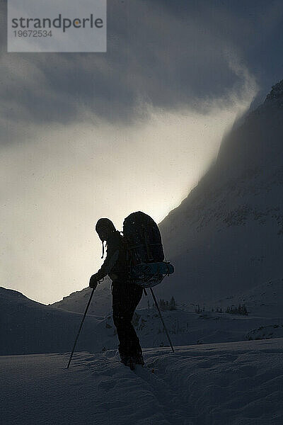 Silhouette eines Backcountry-Skifahrers in den Bergen.