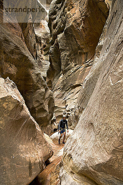 Ein Mann wandert einen Slot Canyon in der Wüste von Utah hinunter.
