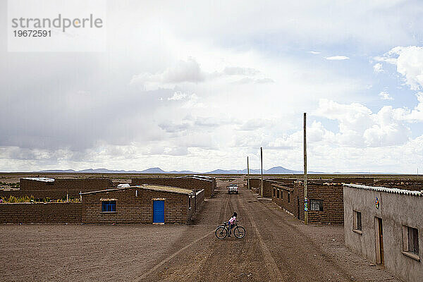 Ein Mädchen fährt Fahrrad in einem kleinen Dorf am Rande der Atacama-Wüste in Bolivien.